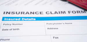Close-up of an insurance claim form with insured details fields, highlighting policy information and personal data sections
