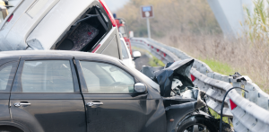 A black car crashes into a guardrail in a severe highway accident involving multiple vehicles