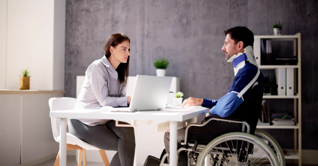 A man on a wheelchair talking to a girl behind a computer