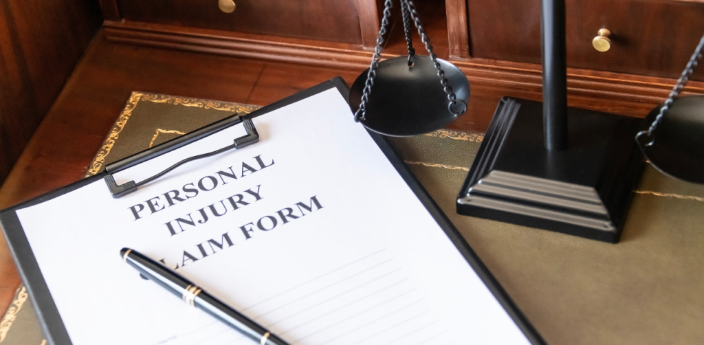 Personal injury claim form on a lawyer’s desk with a pen and scales of justice, representing legal assistance from a car accident lawyer