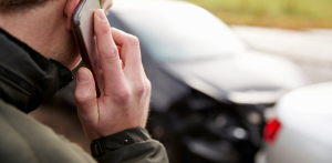 Man on phone near two damaged cars after an auto accident