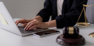 Attorney working on laptop with gavel and scales of justice on desk