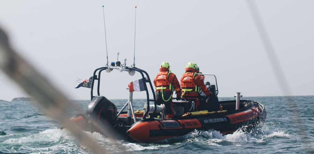 Two rescue workers in bright gear ride a fast response boat during a marine emergency