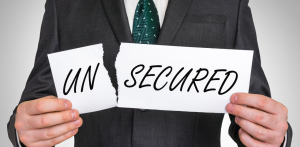 A man in a suit holding two torn pieces of paper reading UN and SECURED, symbolizing division or lack of security