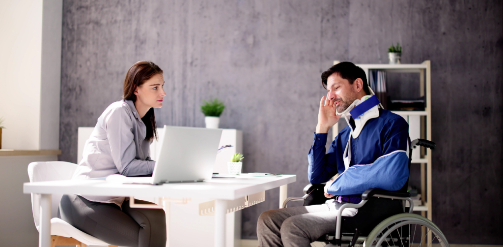 Injury Consultation - A man in a wheelchair with a neck brace talks to a lawyer in a modern office