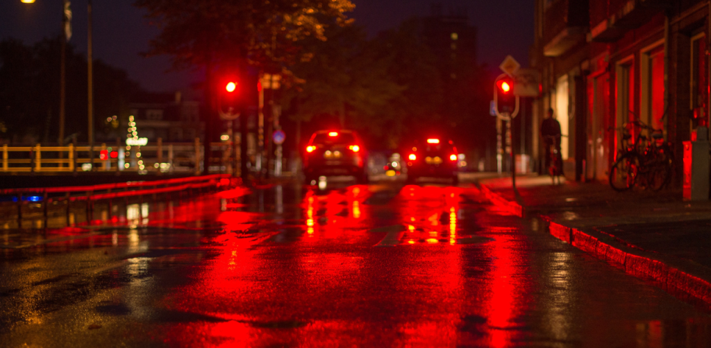 Cars at a red light on a rainy night, emphasizing low-light visibility and pedestrian safety