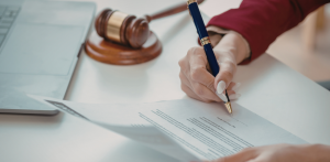 Client signing legal agreement beside gavel during injury case review