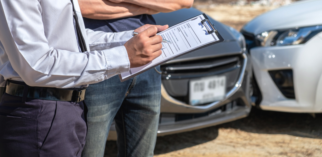 Insurance agent takes notes after crash, helping driver start a car accident claim process