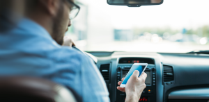 Driver looks at smartphone behind the wheel, showing distracted driving behavior