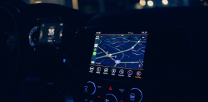 Interior of a car at night with a dashboard navigation screen displaying a map and illuminated controls glowing blue