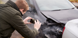 Man takes photo of crash damage, part of truck driver safety and accident documentation