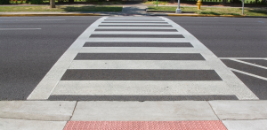 Freshly painted crosswalk leading to a sidewalk with greenery