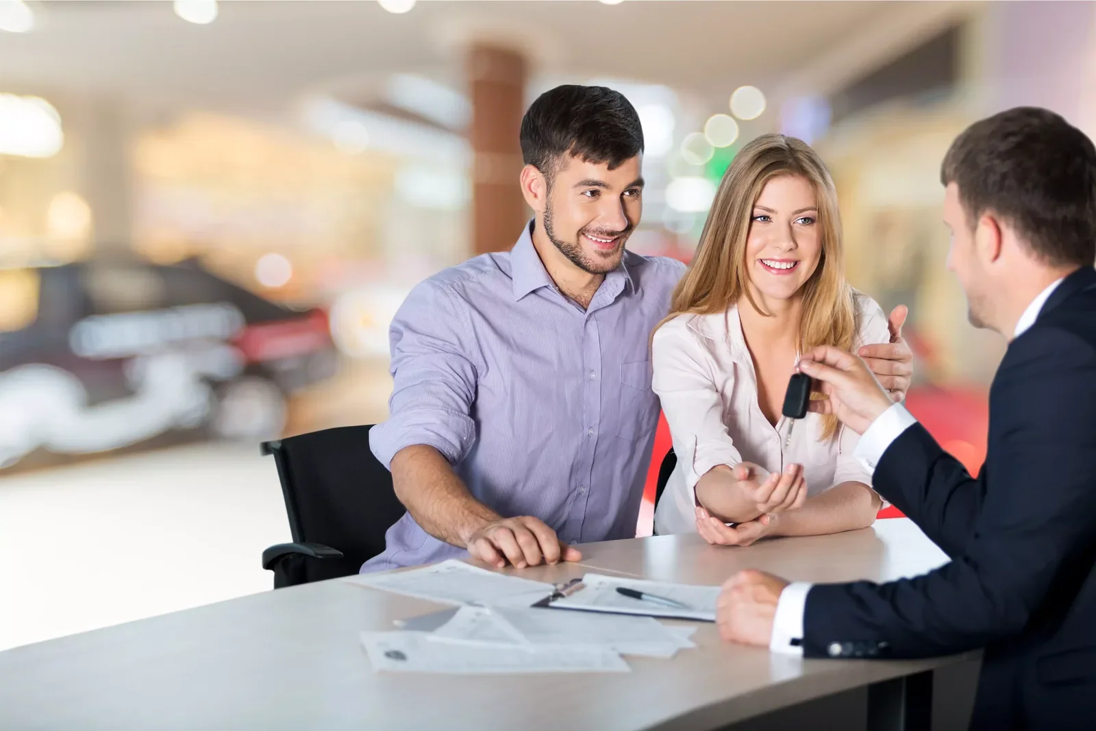 Couple receiving keys after finalizing vehicle financing with a specialist