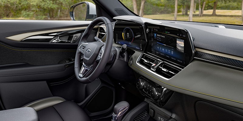 Modern car interior showing the driver's seat, steering wheel, digital gauge cluster, and large infotainment screen.