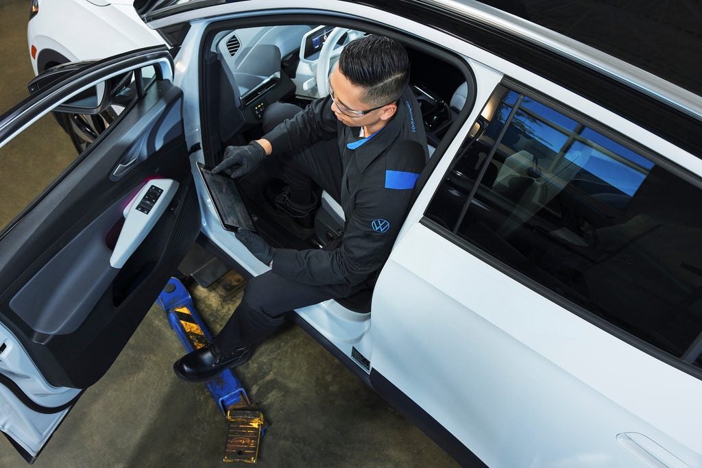 A white vehicle is parked indoors, likely in a service bay or repair shop.