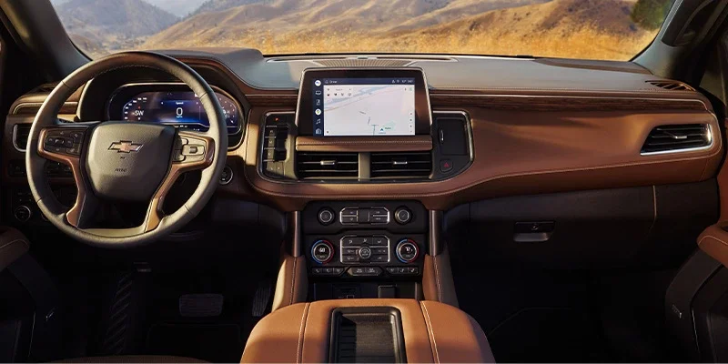 Car interior with a Chevrolet steering wheel, digital dash, and infotainment screen showing a map, against a mountain backdrop.