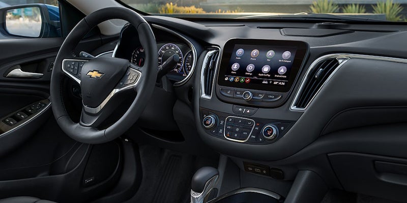 Modern car interior with steering wheel, digital display, and climate controls.