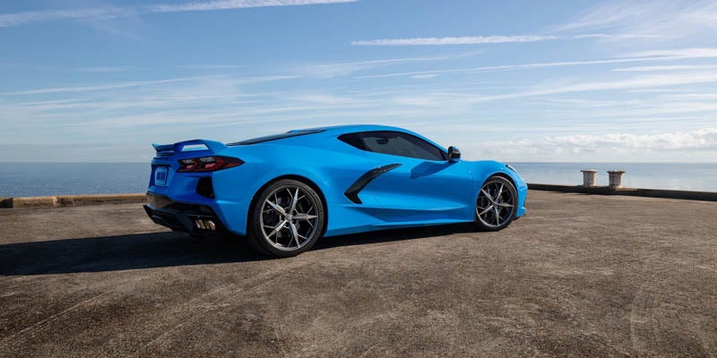 Blue Chevrolet Corvette Stingray sports car parked on a waterfront concrete overlook