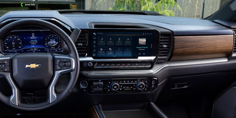 Modern Chevrolet car interior showing the steering wheel, digital instrument cluster, and large touchscreen infotainment system.