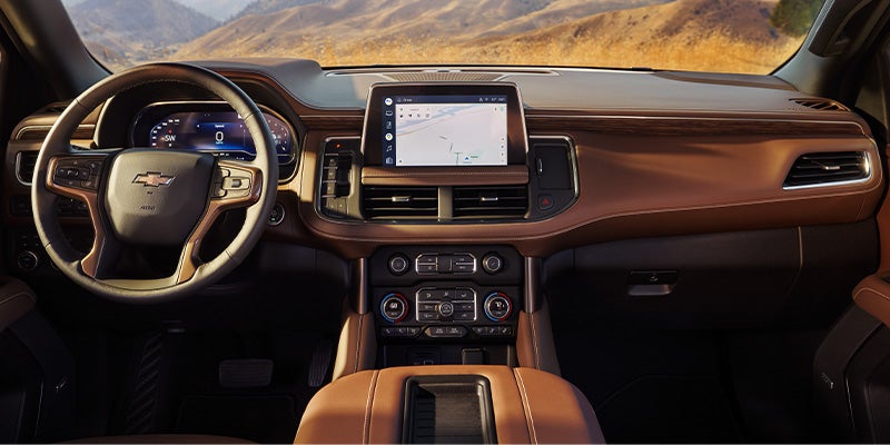 Modern car interior with brown leather dashboard, digital instrument cluster, and central touchscreen navigation display.
