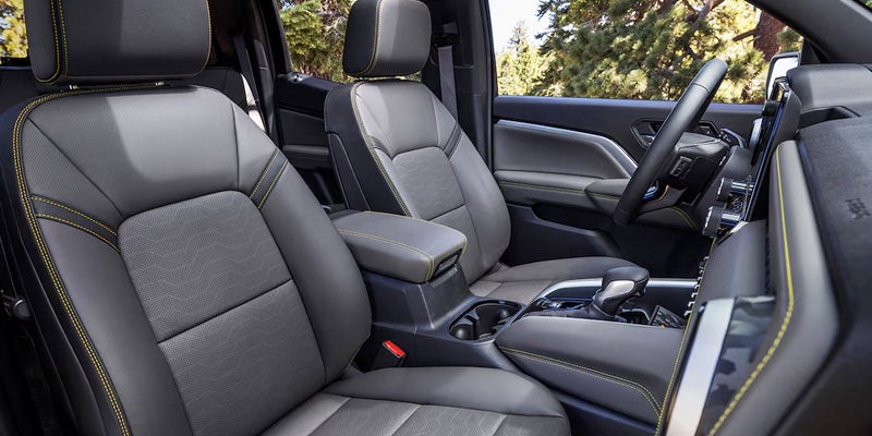 Car interior with gray and black leather seats, yellow stitching, and a center console.