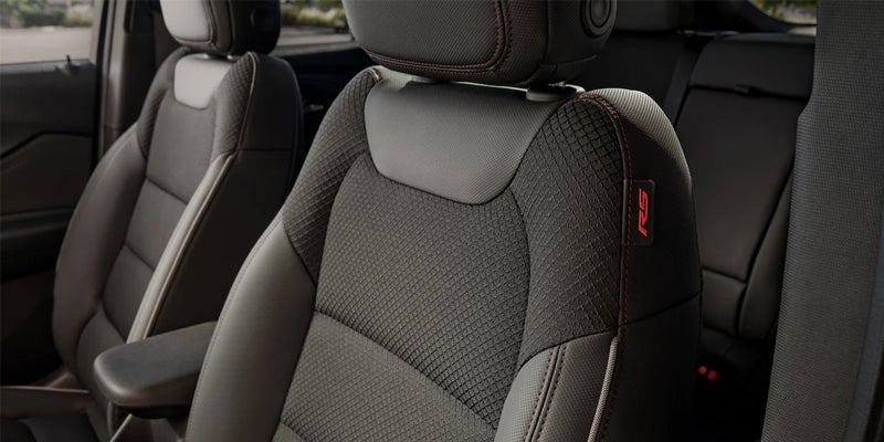Front passenger seat of a car, dark gray with textured inserts, red stitching, and a red "RS" logo.