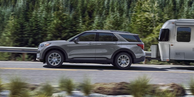 Grey 2025 Ford Explorer towing a travel trailer on the highway