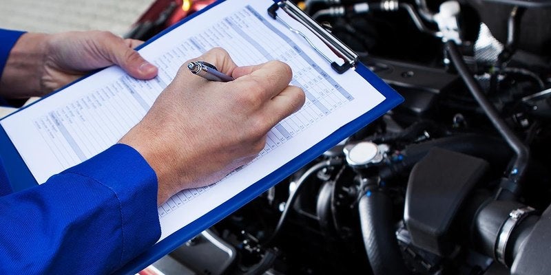 Service adviser filling out a checklist under the hood