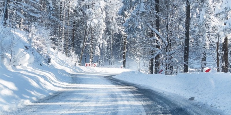 Snow-covered road winding through a forest in winter