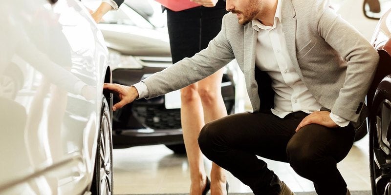 Salesperson showing a vehicle to a customer on the lot