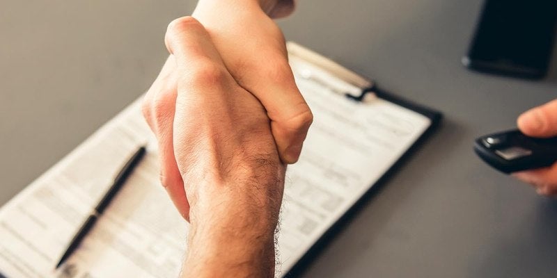 Handshake over a desk at a dealership
