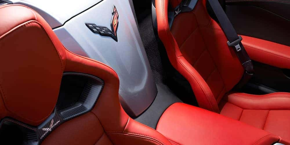 Red leather bucket seats and a white center console with a Corvette logo inside a car.