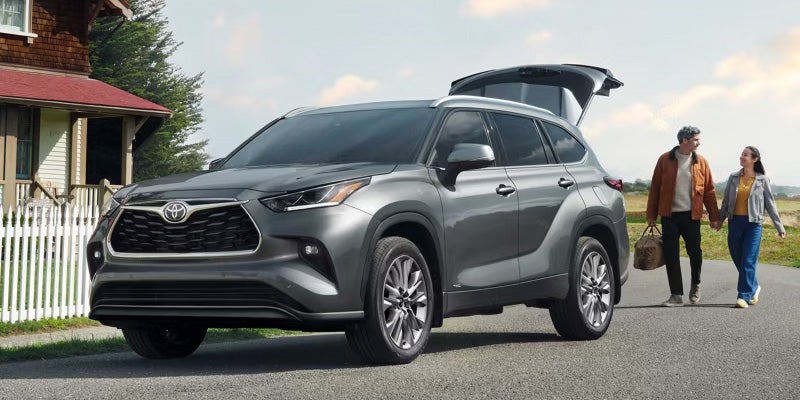 2026 Toyota Highlander three-row SUV with family loading cargo through the open liftgate