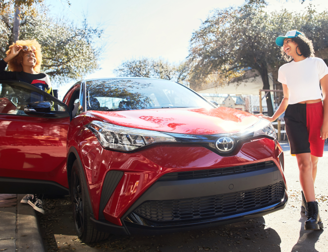 Two people enjoying the sunny day in a red Toyota
