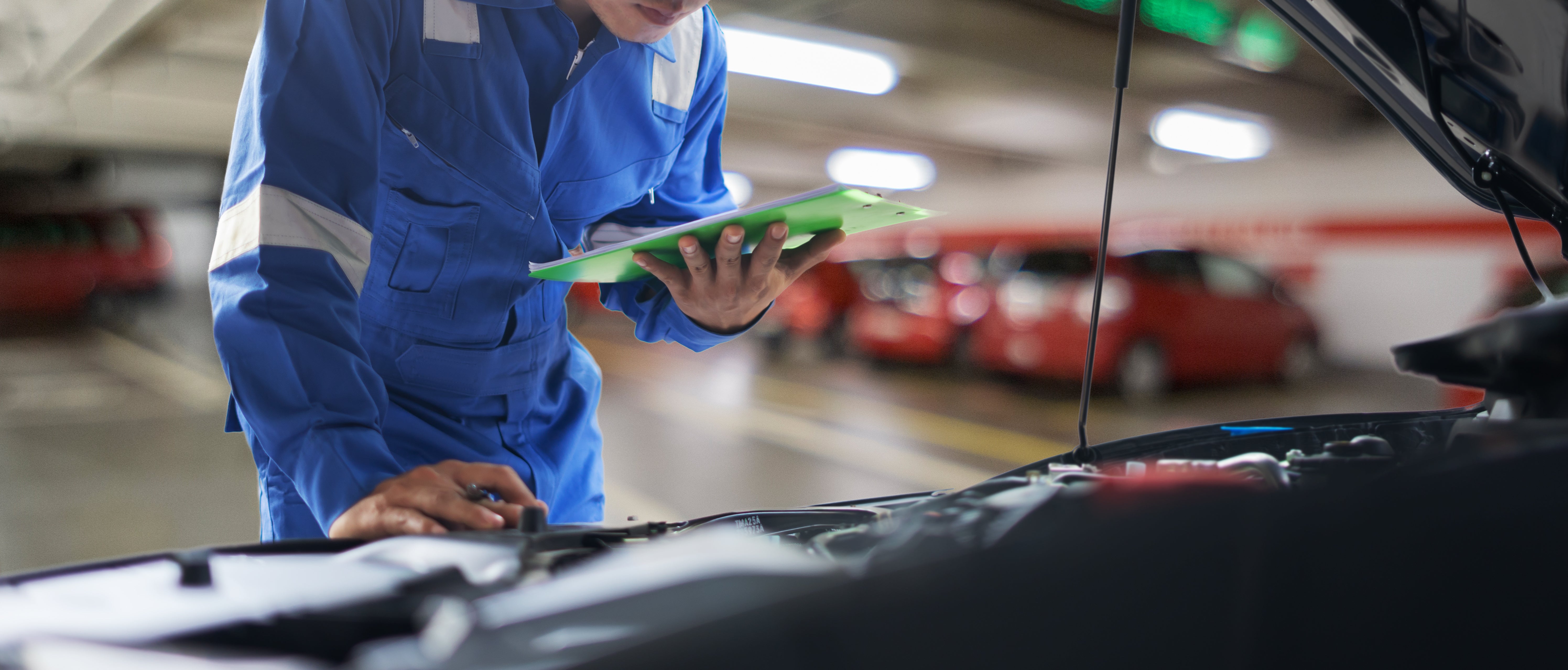 car service, repair, maintenance concept - Asian auto mechanic man or Smith writing to the clipboard at workshop warehouse, technician doing the checklist for repair machine a car in the garage,banner
