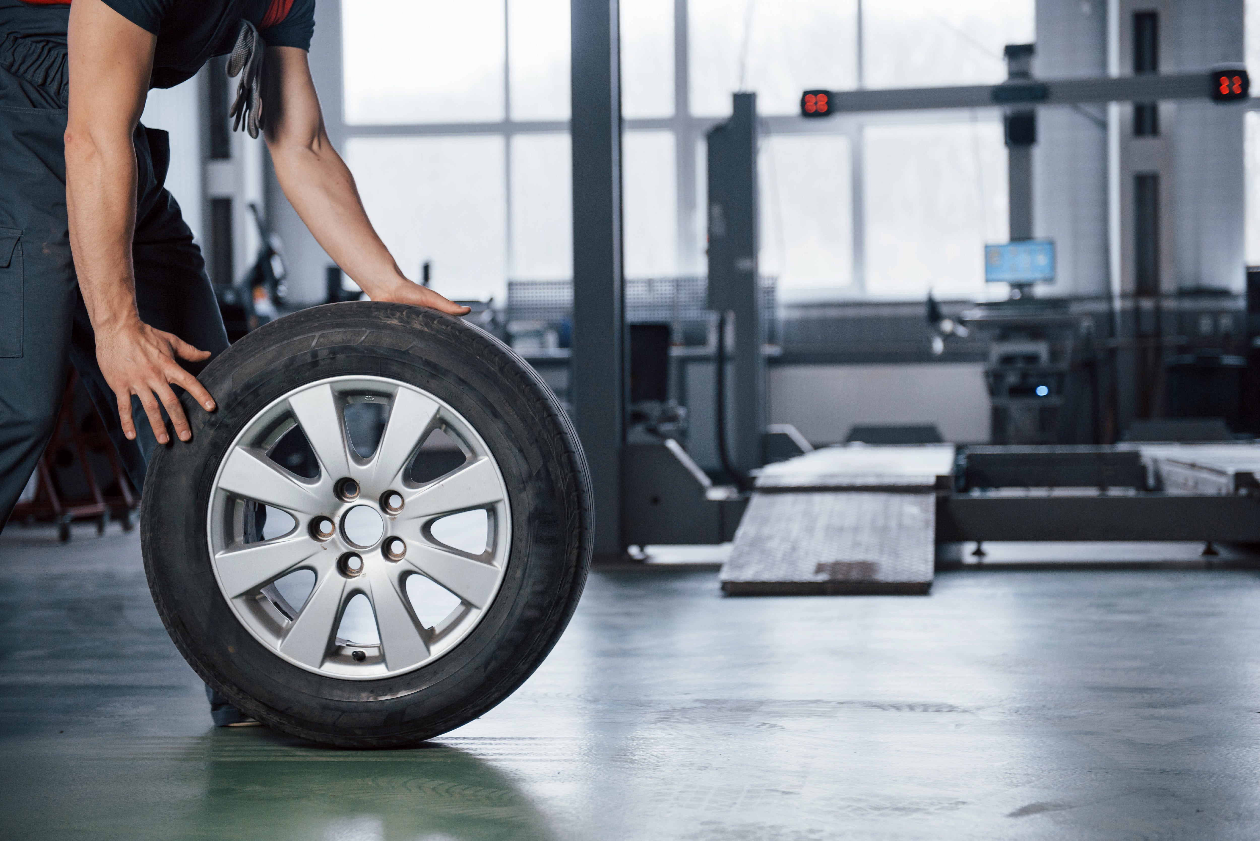 Grounded view. Mechanic holding a tire at the repair garage. Replacement of winter and summer tires