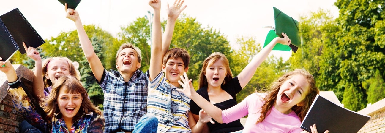 Students laughing and cheering while holding their notebooks.