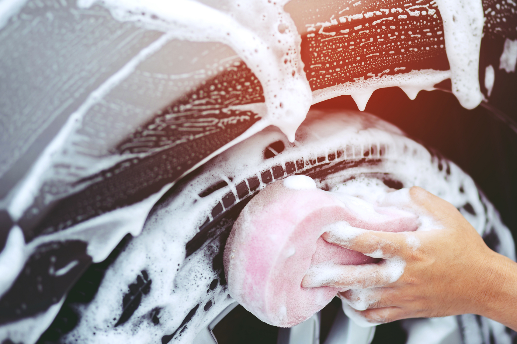 Man hand washing car tires with a sponge