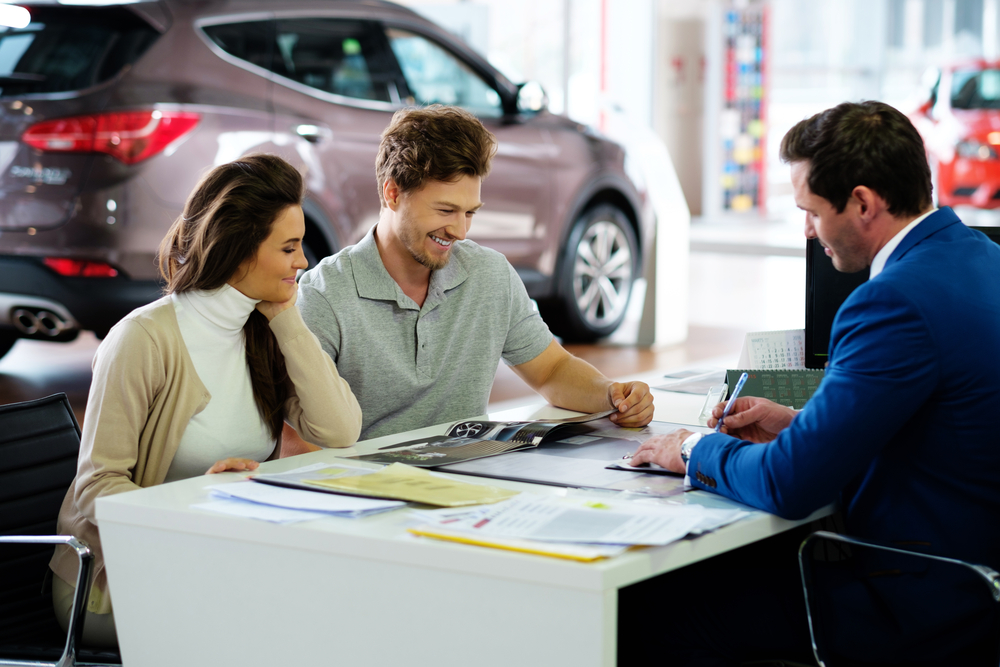 Couple completing car finance application at dealership