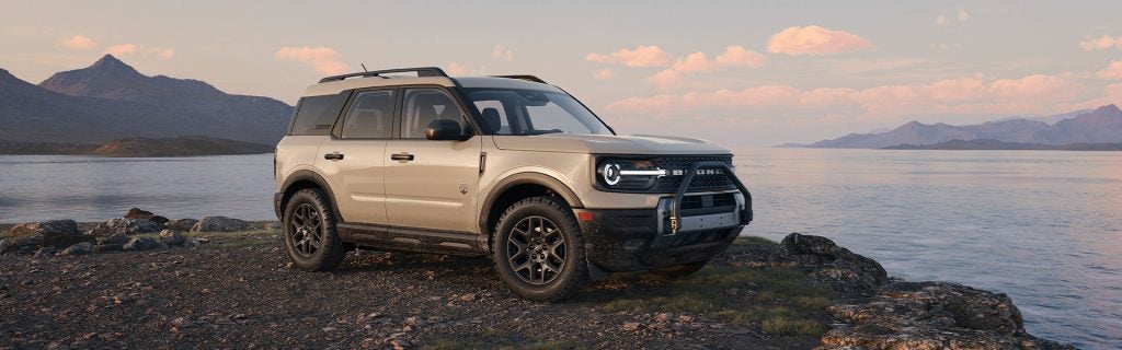 Exterior of beige 2025 Ford Bronco sport SUV that is parked on a rocky beach by a body of water near McMinnville, OR