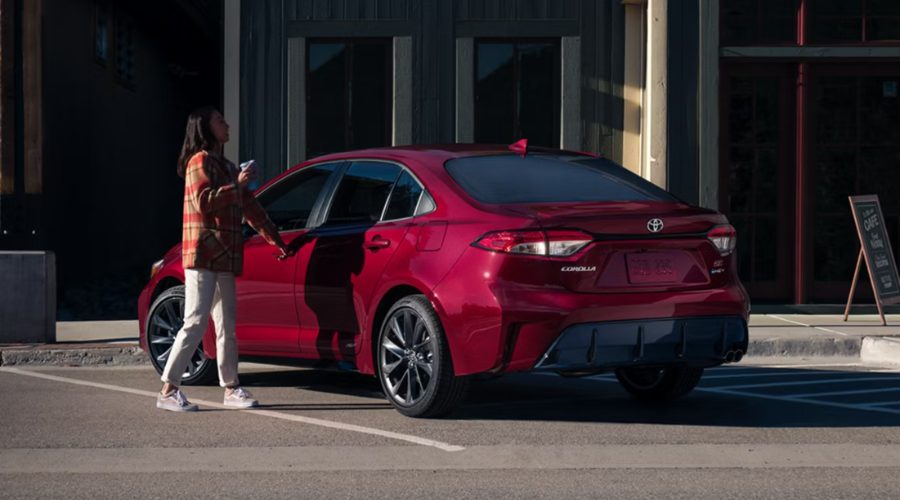 A driver opening the door of a red 2026 Toyota Corolla Hybrid SE AWD, highlighting practical daily utility and style for commuters in the Waukegan and Gurnee, IL areas.
