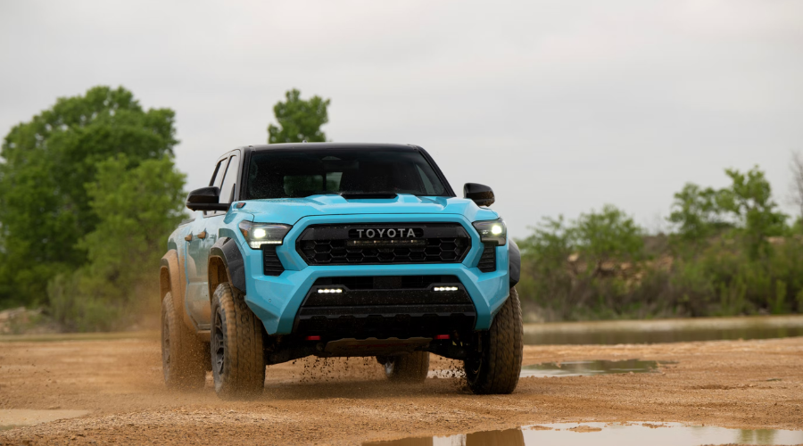 Front view of a bright blue 2026 Toyota Tacoma TRD Pro kicking up dust on a dirt trail, highlighting midsize off-road capability and aggressive LED styling for Lake County truck enthusiasts near Round Lake and Waukegan, IL.