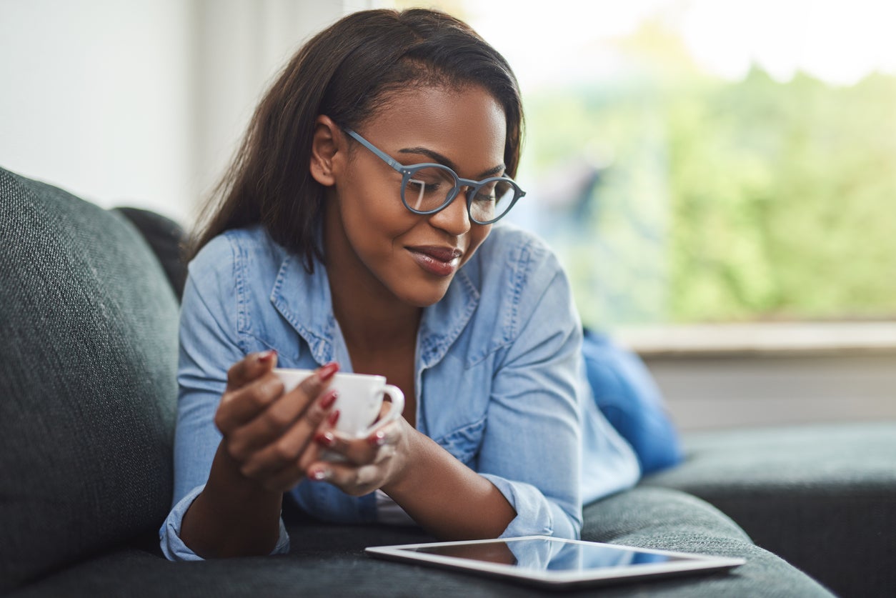 Young woman relaxing at home browsing online with a coffee