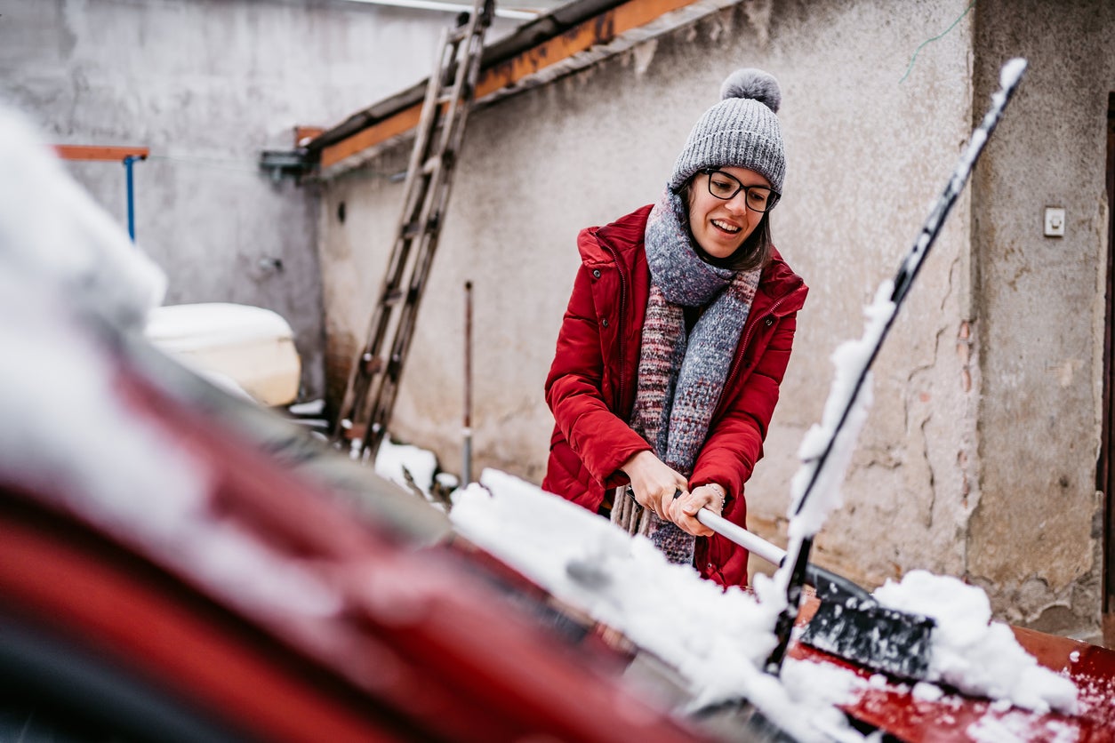 Woman cleaning snow off her car