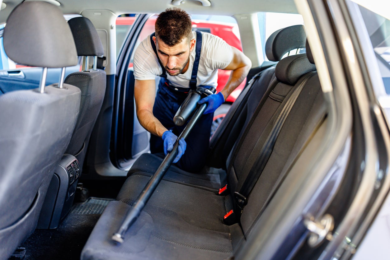 A Young Man is Cleaning Car Interior with Vacuum Cleaner.
