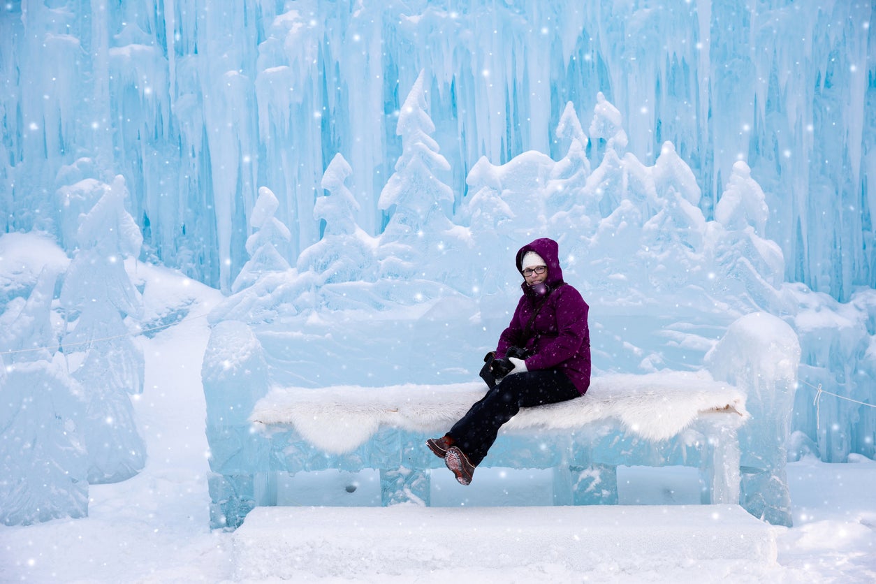 woman sitting on an ice bench at the ice castles