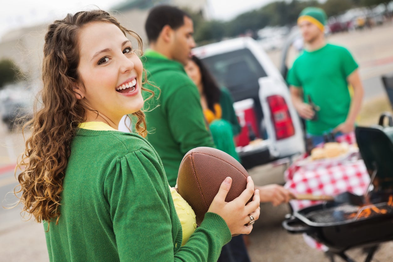 Cute college girl tailgating at stadium with football fans