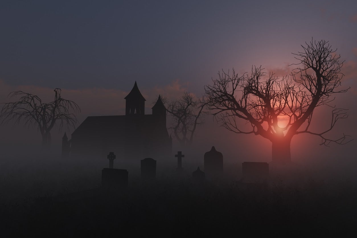 Scene of a church graveyard on a foggy sunset for Halloween.