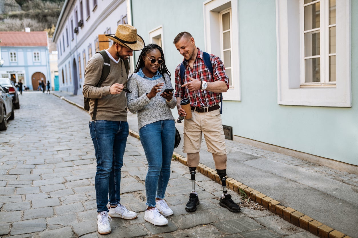 Diverse youth with man with prosthetic legs looking at GPS on smart phone