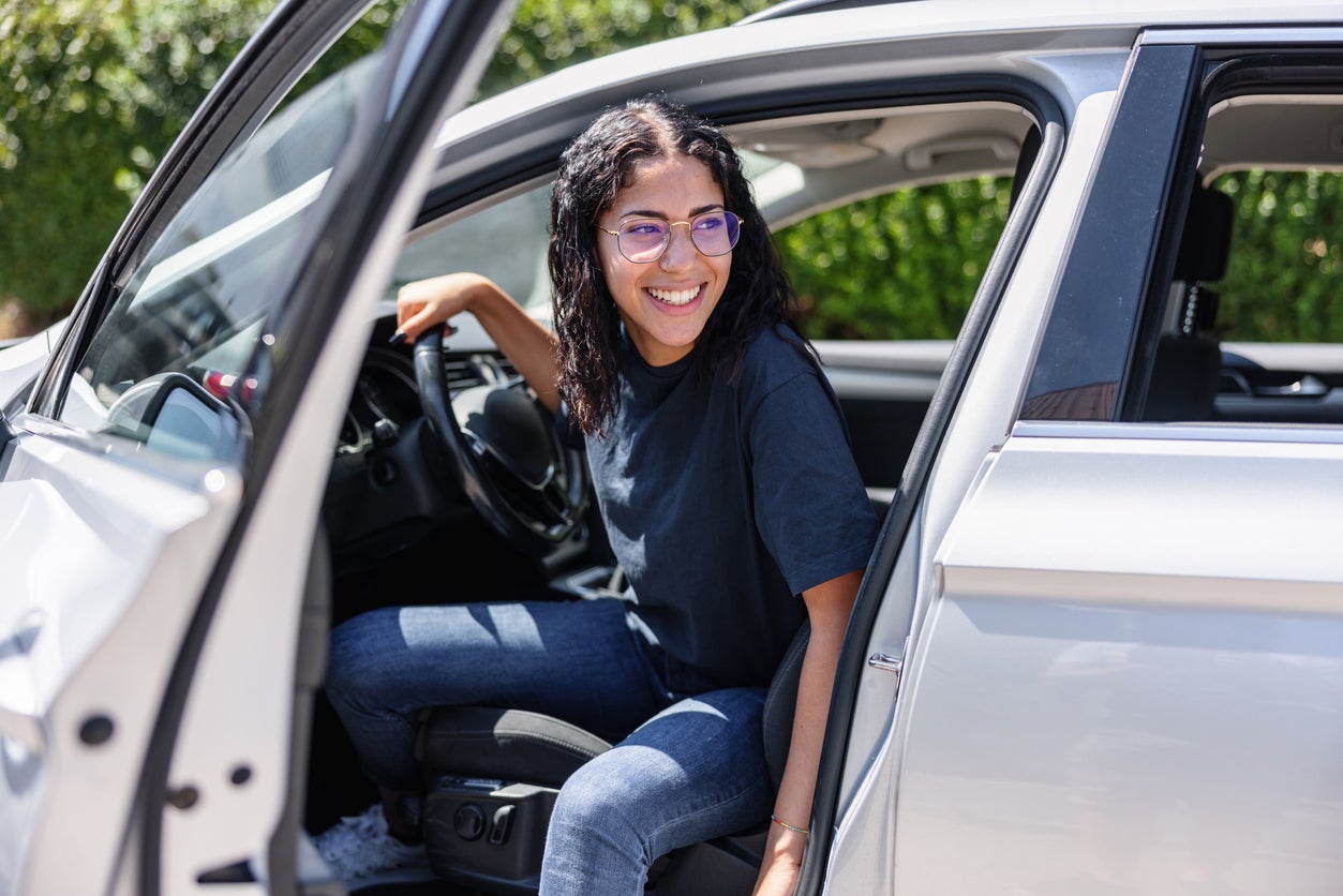 Young Latin Female Trying To Get Out Of A Car. She Is Giggling
